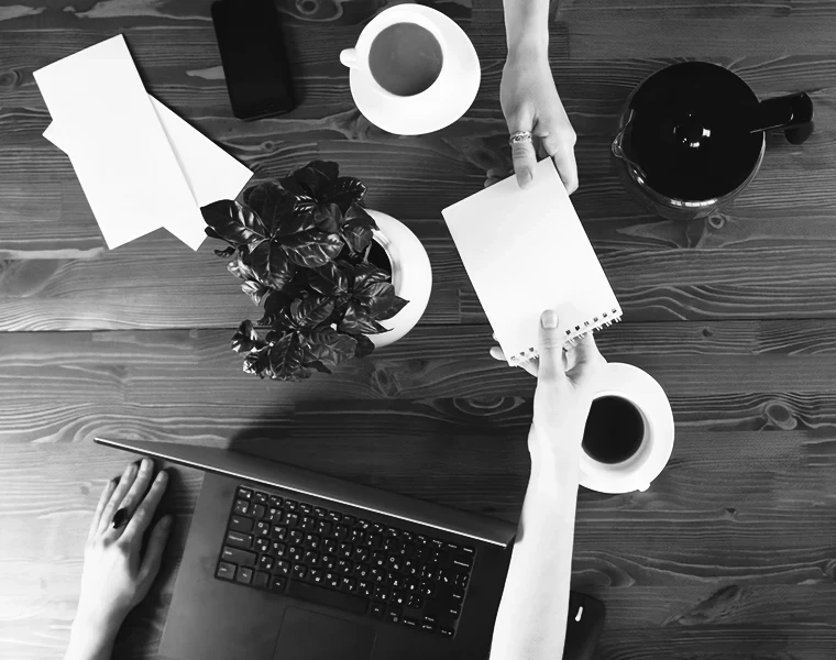 Vue en plongée d'un bureau où deux personnes échangent un carnet
